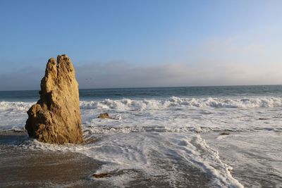 Rock formation on beach against sky