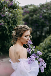 A delicate elegant young woman bride in a wedding dress walks in a blooming spring outdoor park
