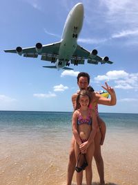 Portrait of happy girl standing on airplane at beach