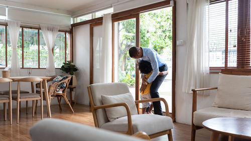 Boy embracing father on doorway at home