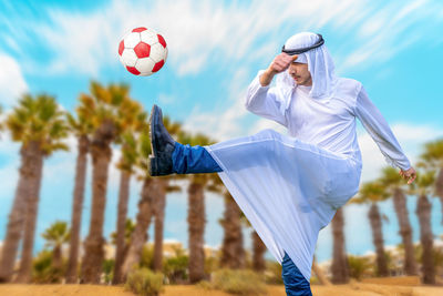 Rear view of man playing soccer at park