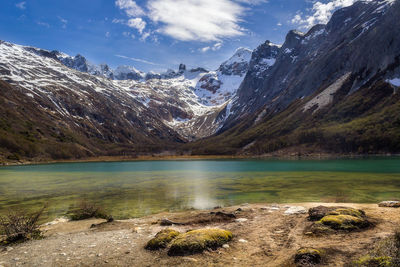 Scenic view of lake by snowcapped mountains against sky