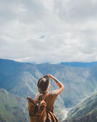 Rear view of person standing on mountain against sky