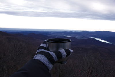 Midsection of person holding umbrella against mountain range