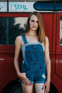 Portrait of beautiful young woman standing against red wall