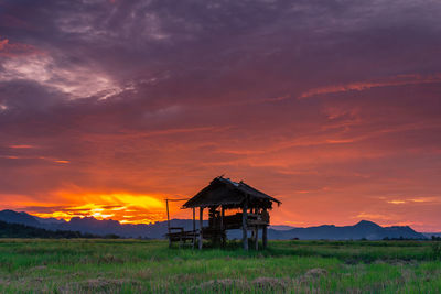 Lifeguard hut on field against sky during sunset