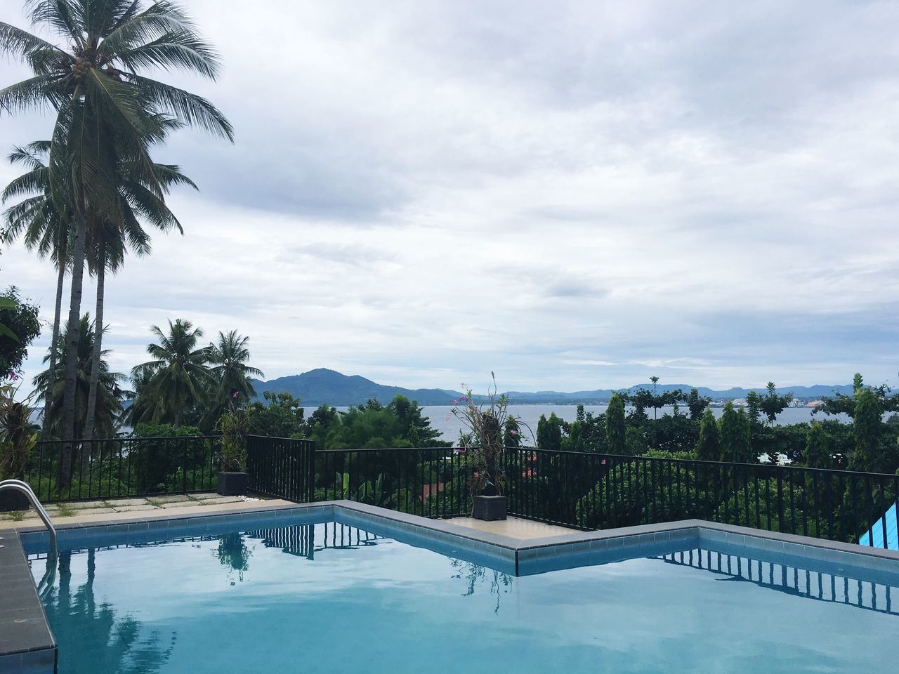 swimming pool, water, tree, palm tree, tourist resort, sky, tranquil scene, vacations, tranquility, no people, cloud - sky, outdoors, luxury, day, luxury hotel, scenics, nature, beauty in nature, architecture