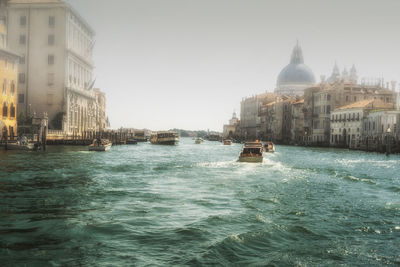 Boats in canal amidst buildings against sky