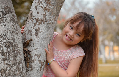 Portrait of smiling girl standing by tree