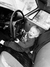 Portrait of cheerful boy sitting in car