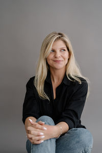 Portrait of young woman sitting against wall