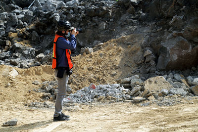 Medium close picture of a photographer taking pictures with rocks on the back