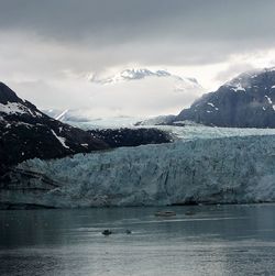 Scenic view of lake and mountains against cloudy sky during winter