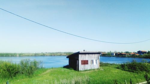 House by lake against sky