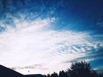 Low angle view of silhouette trees against blue sky