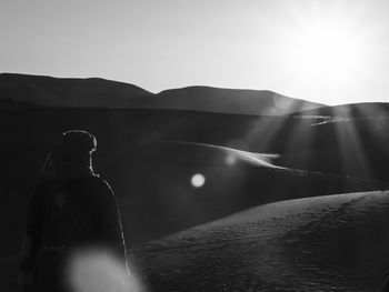 Rear view of man on a desert dune against sky
