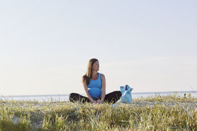 Pregnant woman practicing yoga at seaside