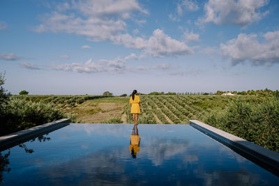 Rear view of man standing by plants against sky