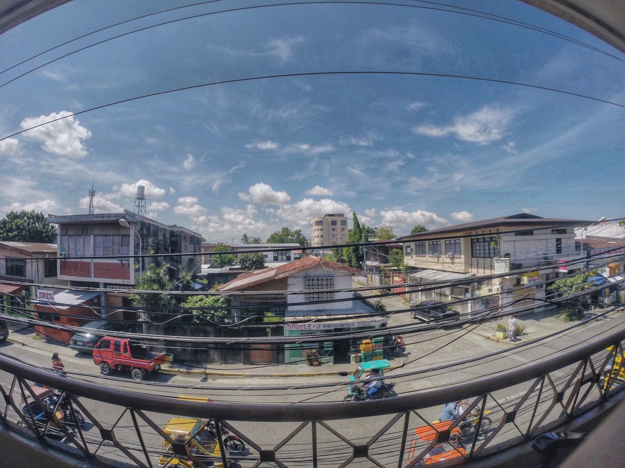 architecture, built structure, building exterior, sky, cloud - sky, cloudy, city, cloud, transportation, high angle view, day, incidental people, residential building, railing, residential structure, city life, mode of transport, fish-eye lens, outdoors, tree