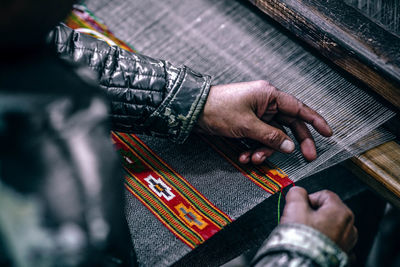 Midsection of person knitting textile in factory