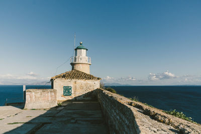 Lighthouse by sea against sky