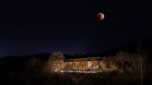 Low angle view of moon over illuminated building at night