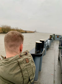 Rear view of man standing by sea against sky