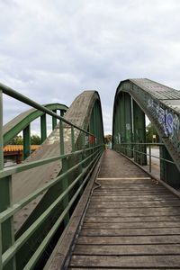 Bridge over footbridge in city against sky