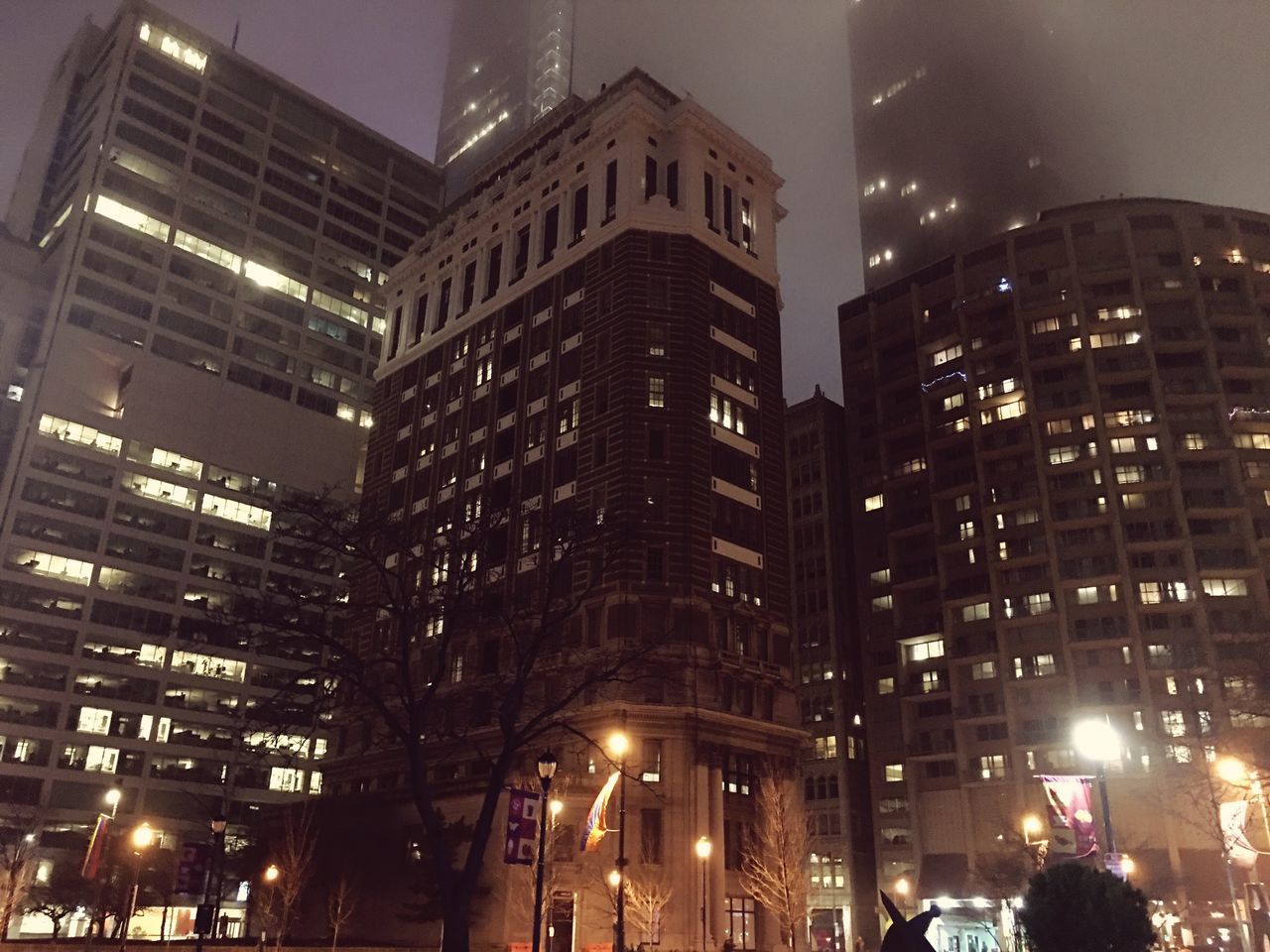 LOW ANGLE VIEW OF ILLUMINATED SKYSCRAPERS AT NIGHT