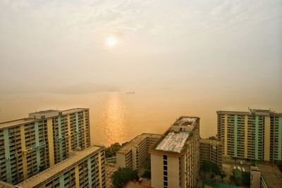 High angle view of buildings by sea against sky during sunset