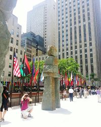 Statues in city against sky