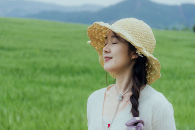 Young woman wearing hat standing on field