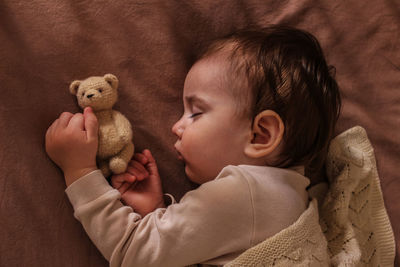 The kid sleeps sweetly with the teddy bear