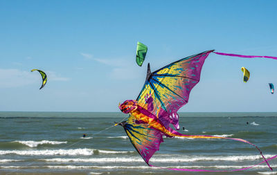 A dragon kite flies over the beach alongside kite boarders on lake michigan usa