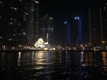 Illuminated buildings by river at night