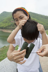 Mother helping son in using binoculars against mountains