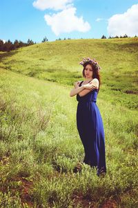 Full length of smiling young woman standing on field against sky