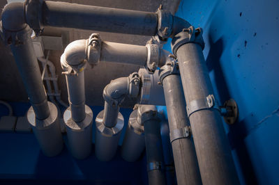 Low angle view of pipes against blue sky