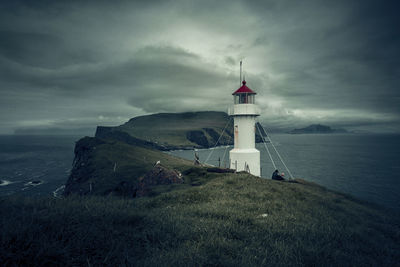 Lighthouse by sea against sky