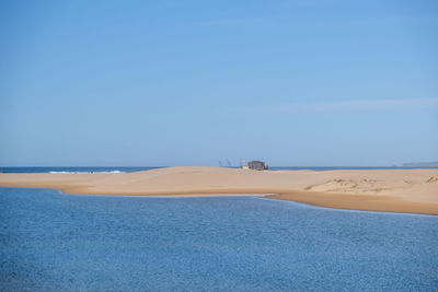 Scenic view of beach against clear blue sky