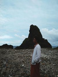 Side view of woman standing at beach against sky