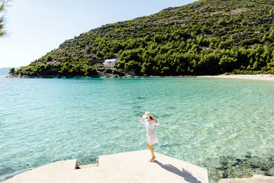 Full length of young woman with arms outstretched standing at beach