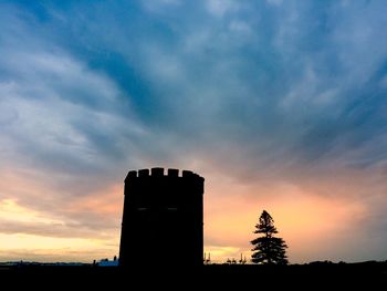 Low angle view of silhouette building against sunset sky