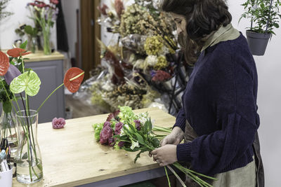 Side view of woman by potted plant on table