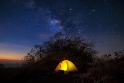 Illuminated tent on field against sky at night