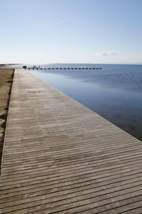 Boardwalk by sea against sky