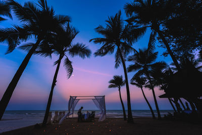 Silhouette palm trees on beach against sky during sunset