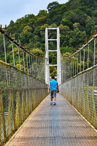 Rear view of boy walking on footbridge