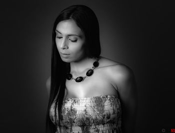 Close-up of young woman standing against black background