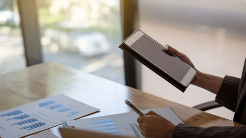 Cropped image of woman using digital tablet at office